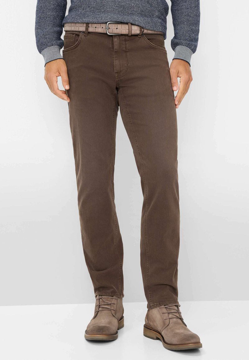 Pantaloni in cotone marroni con piedi dritti, dotati di chiusura frontale con bottone e zip, e una cintura texturizzata color beige. Indossati con stivali marroni chiari.