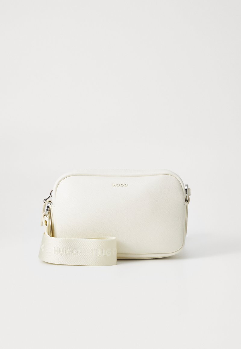 White crossbody bag with a textured surface, zip closure, and adjustable strap featuring embossed branding. Rectangular shape with soft edges.
