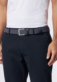 Cintura intrecciata con un motivo a zigzag navy e bianco, dotata di una fibbia rettangolare in metallo argento e un accento in pelle nera.