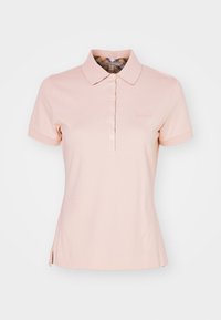 Camisola polo rosa clara feita de tecido de algodão liso, apresentando uma pala com botões, mangas curtas e um logótipo bordado discreto no peito.