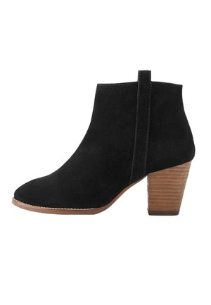 Bota de ante negro hasta el tobillo con tacón de bloque apilado de madera y lengüeta en la parte trasera, con punta redondeada y costura lateral.