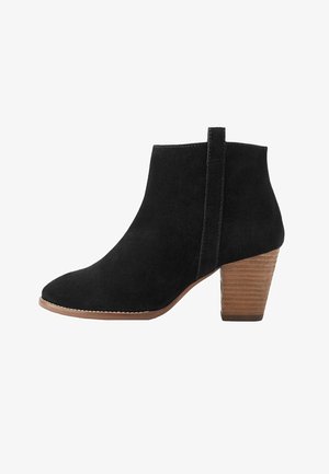 Musta mokkanahkainen nilkkuri, jossa on pinottu puinen paksukanta ja vetoluukku takana, pyöristetty kärki ja sivusaumaukset.