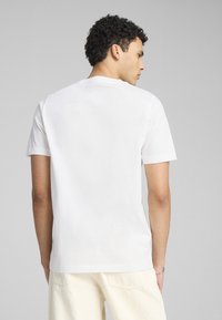 Camiseta de algodón blanca con mangas cortas, cuello redondo y una textura suave. La parte de atrás muestra un diseño sencillo sin gráficos ni adornos.
