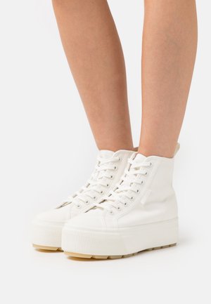 Baskets montantes en toile blanche avec une surface texturée, une semelle plateforme épaisse et des lacets plats, dotées d'une languette de traction à l'arrière.
