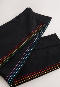 Pantaloni sportivi neri con strisce di strass colorati in arancione, verde, viola, blu e rosa, che accentuano i lati, con una texture liscia.