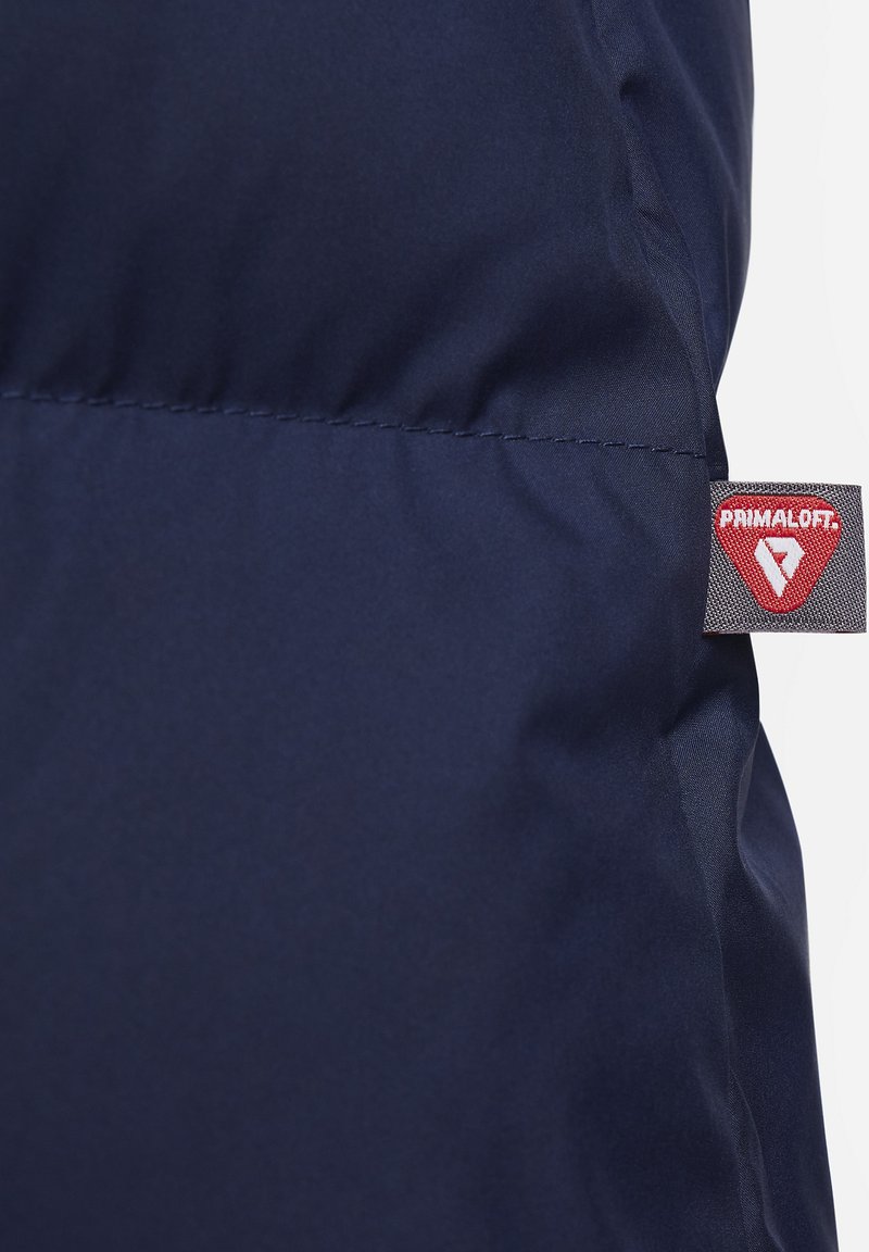 Marineblaue Stoff mit glatter Textur, versehen mit einem Primaloft-Label. Das Design ist schlicht, ohne sichtbare Muster oder Hardware.