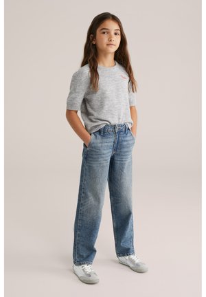 Maglione a maniche corte grigio in maglia con ricamo rosso, abbinato a jeans a vita alta blu a gamba larga e scarpe sportive bianche.