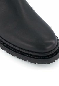 Bottines en cuir noir avec un orteil rond, surface texturée, coutures renforcées et semelle en caoutchouc robuste.