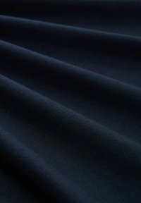 Donkerblauwe stof met een fijne textuur, weergegeven in zachte plooien die subtiele diagonale schaduw- en lichteffecten creëren.