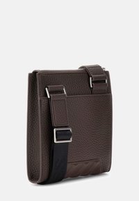 Brązowa torba ze skóry o fakturze, z zamkiem błyskawicznym, regulowanym czarnym paskiem i srebrnymi okuciami. Na przedniej części znajduje się subtelny wzór.