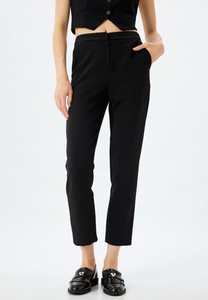Zwarte gepaste broeken met een slim fit, met een gladde textuur, zijzakken en een platte tailleband, gecombineerd met zwarte instappers.