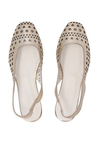 Des chaussures plates beiges avec des motifs de triangles et de cercles découpés, un bout carré et des brides de cheville. Matériau en cuir lisse avec une finition brillante.