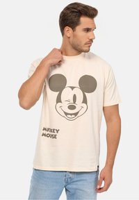 Kermanvärinen puuvillat-paita, jossa on suuri harmaa Mikki Hiiri -grafiikka ja teksti "MICKEY MOUSE" alaosassa. Rentoa mallia, lyhyet hihat.