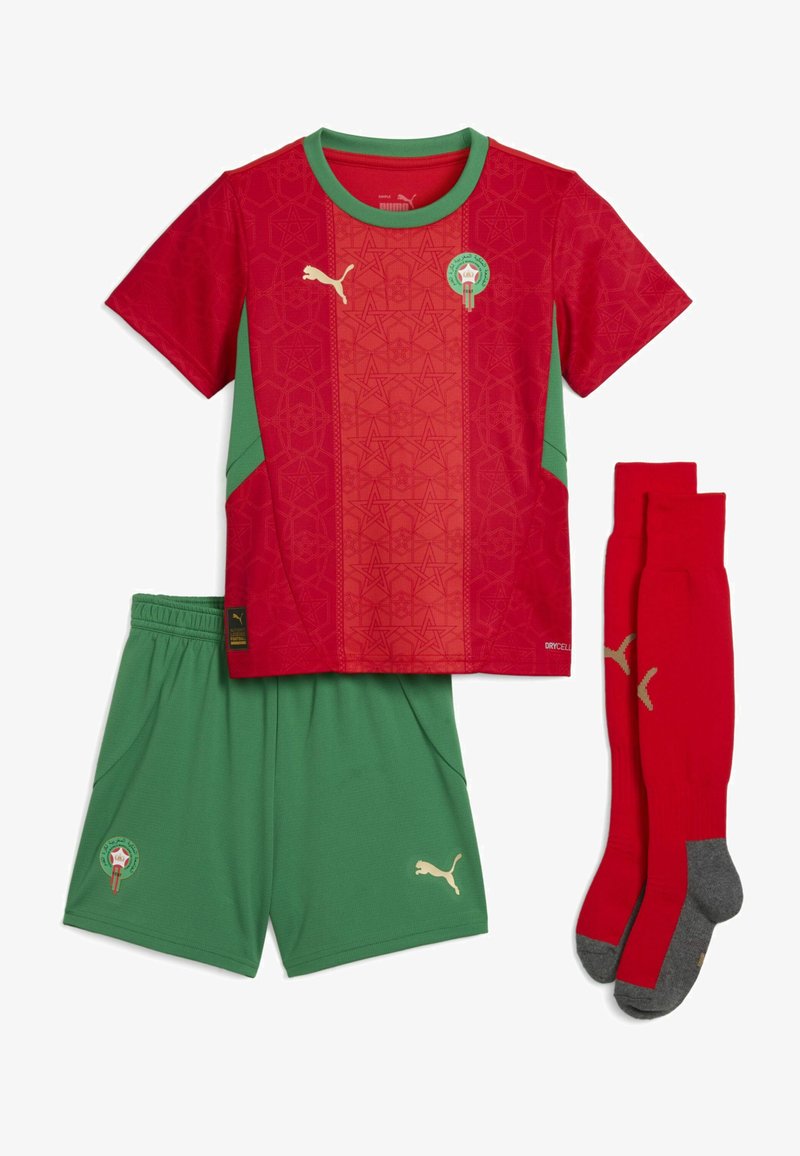 Equipación de fútbol roja y verde que incluye una camiseta de manga corta, pantalones cortos y calcetines. La camiseta tiene un patrón geométrico con un escudo; los pantalones cortos son de color verde liso.