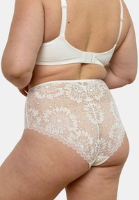 Culottes blanches en dentelle taille haute avec des motifs floraux et des bords festonnés, accompagnées d'un soutien-gorge blanc uni avec des bretelles réglables.
