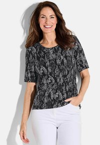 Haut noir à manches courtes avec un motif abstrait texturé blanc. Encolure ronde et coupe décontractée. Assorti avec un pantalon blanc.