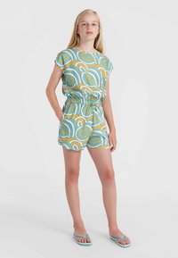 Gemusterter Overall in Türkis, Gelb und Weiß, mit kurzen Ärmeln, elastischem Bund und Taschen; kombiniert mit blauen Flip-Flops.