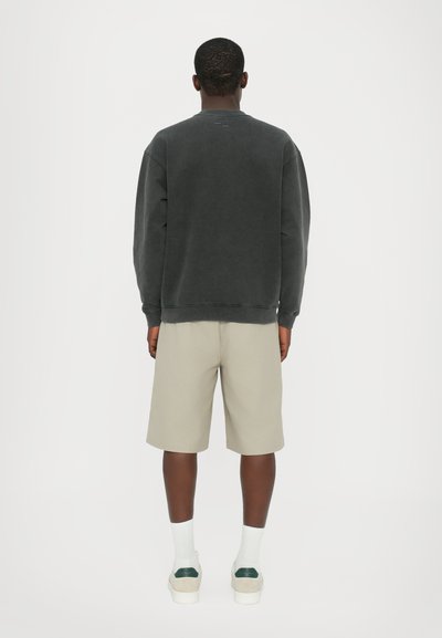 Mørkegrå fleece-sweater med ribbede manchetter, parret med lysebeige knælange shorts og hvide ankelstrømper. Blød, afslappet stil.