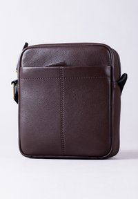 Brown leather crossbody bag with textured surface, featuring a front pocket and zip closure. Square shape with adjustable strap.