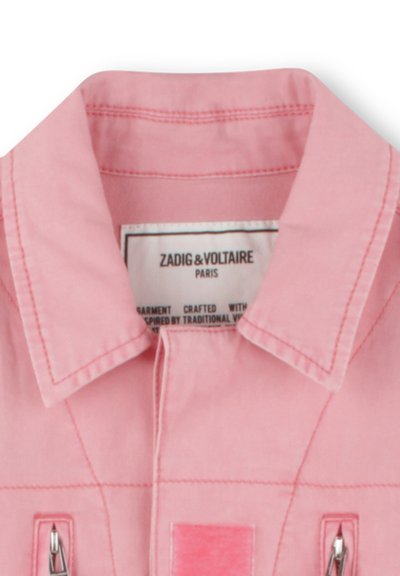 Chemise en coton rose avec un col, des zips à l'avant et une poche rectangulaire. Étiquette de la marque visible à l'intérieur du col avec des instructions d'entretien.