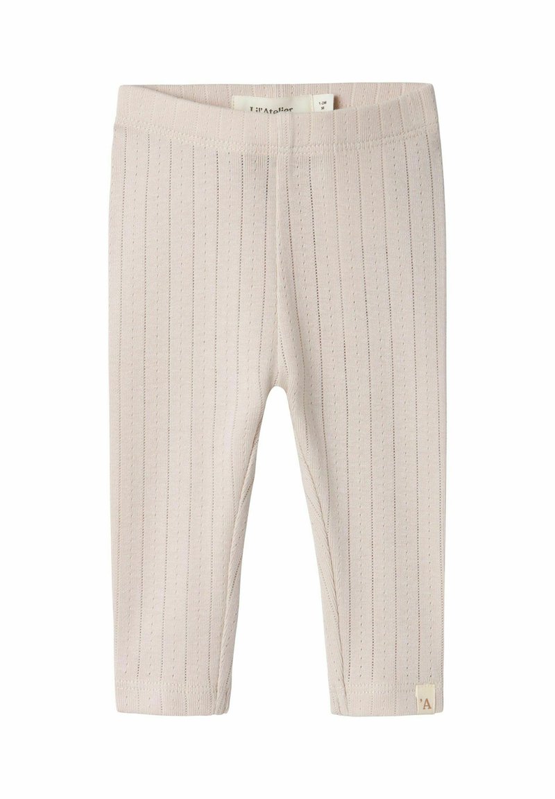 Leggings côtelés de couleur beige clair en tissu doux, avec une taille élastique et une petite étiquette sur l'ourlet.