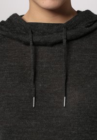 Un hoodie gris foncé en tissu doux et texturé. Il présente un col montant, des cordons de serrage avec des embouts en métal, et une coupe décontractée.