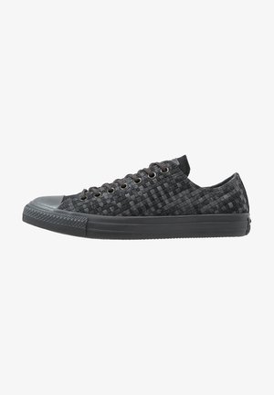 Black woven sneakers with a rubber toe cap, round laces, and a textured pattern. Features a low-profile design and padded collar.