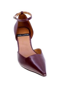 Scarpa con tacco alto in pelle marrone con punta affusolata e cinturino alla caviglia. Presenta un decolté basso e una superficie liscia. Etichetta del marchio visibile all'interno.