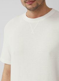 Witte katoenen t-shirt met ronde hals en korte mouwen, met een textuurstof en een gestikte detail bij de halslijn.