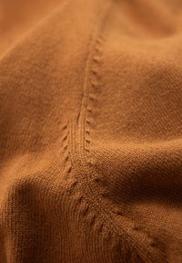 Brauner gestrickter Stoff mit glatter Textur und dezentem Glanz. Verfügt über dekorative Nähte entlang der Nähte, die einen geschichteten visuellen Effekt erzeugen.