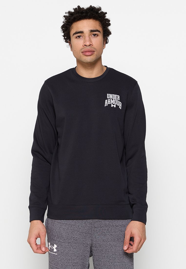 Sudadera negra de tejido suave con cuello redondo y logotipo bordado de 'Under Armour' en el pecho. Combinada con pantalones de chándal grises.