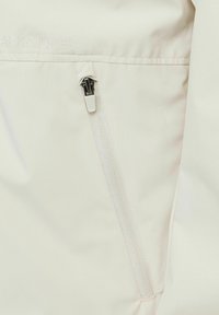 Buzunar crem deschis cu fermoar pe un material neted, cu numele brandului "BLACK & JONES" embosat deasupra într-o culoare subtil contrastantă.