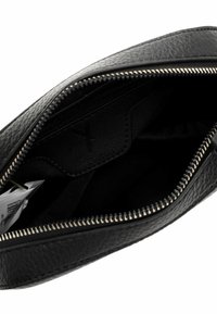Borsa nera in pelle con un esterno texture, chiusura con zip argentata e un interno in tessuto nero, che presenta un dettaglio con tasca per schede.
