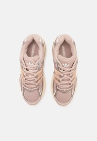 Scarpe sportive rosa chiaro con tomaia in rete, dettagli testurizzati e particolari riflettenti. Dotate di suole in gomma crema e lacci beige.