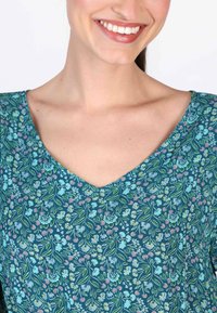 Bluse mit Blumenmuster und V-Ausschnitt, aus weichem Stoff in Teal, verziert mit pinken und hellblauen Blumen.