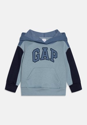 Sudadera azul claro con capucha azul oscuro, mangas azul marino y un gran logo "GAP". Cuenta con un bolsillo frontal y puños acanalados. Textura suave.