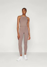 Svetlohnedý športový set pozostávajúci z tielka na ramienka a legín s vysokým pásom. Hladká tkanina s priliehavým siluetou a minimálnym dizajnom.