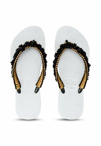 Witte rubberen flip-flops met gestructureerde zolen, voorzien van zwarte kralen en gouden accenten op de banden. Plat ontwerp, geen hakverhoging.