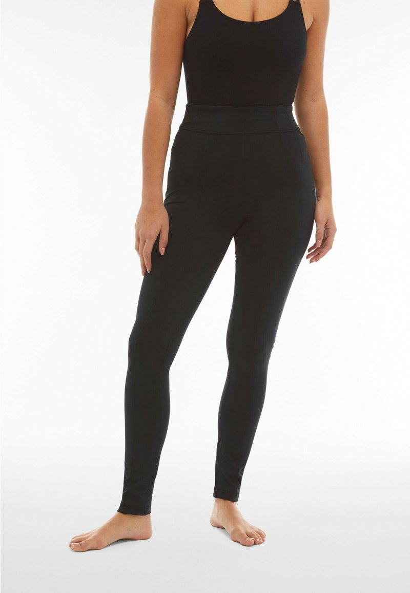 Leggings neri a vita alta realizzati in un tessuto elasticizzato, con un design aderente e una costruzione senza cuciture per il massimo comfort.