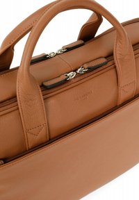 Bruine leren handtas met twee hengsels aan de bovenkant, ritssluitingen, gestructureerde afwerking en details in zilverkleurig metaal.