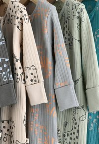 Sample pack of ribbed pajamas in beige, gray, green, and teal, featuring animal prints with contrasting accents and cuffed sleeves.