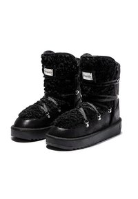 Botas negras con un upper de piel de textura peluda, acentos de cuero, suelas de goma y cordones grises con herrajes metálicos. Diseño de suela plana para estabilidad.