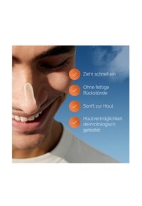 Close-up of a person’s face with light skincare cream on the nose. Background features a blue sky. Four checkmarks list product benefits.