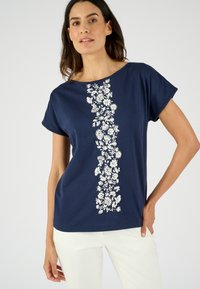 Camiseta de manga corta en color azul marino con un estampado floral blanco en el centro. Material de algodón suave y corte relajado.