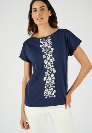 Camiseta de manga corta en color azul marino con un estampado floral blanco en el centro. Material de algodón suave y corte relajado.