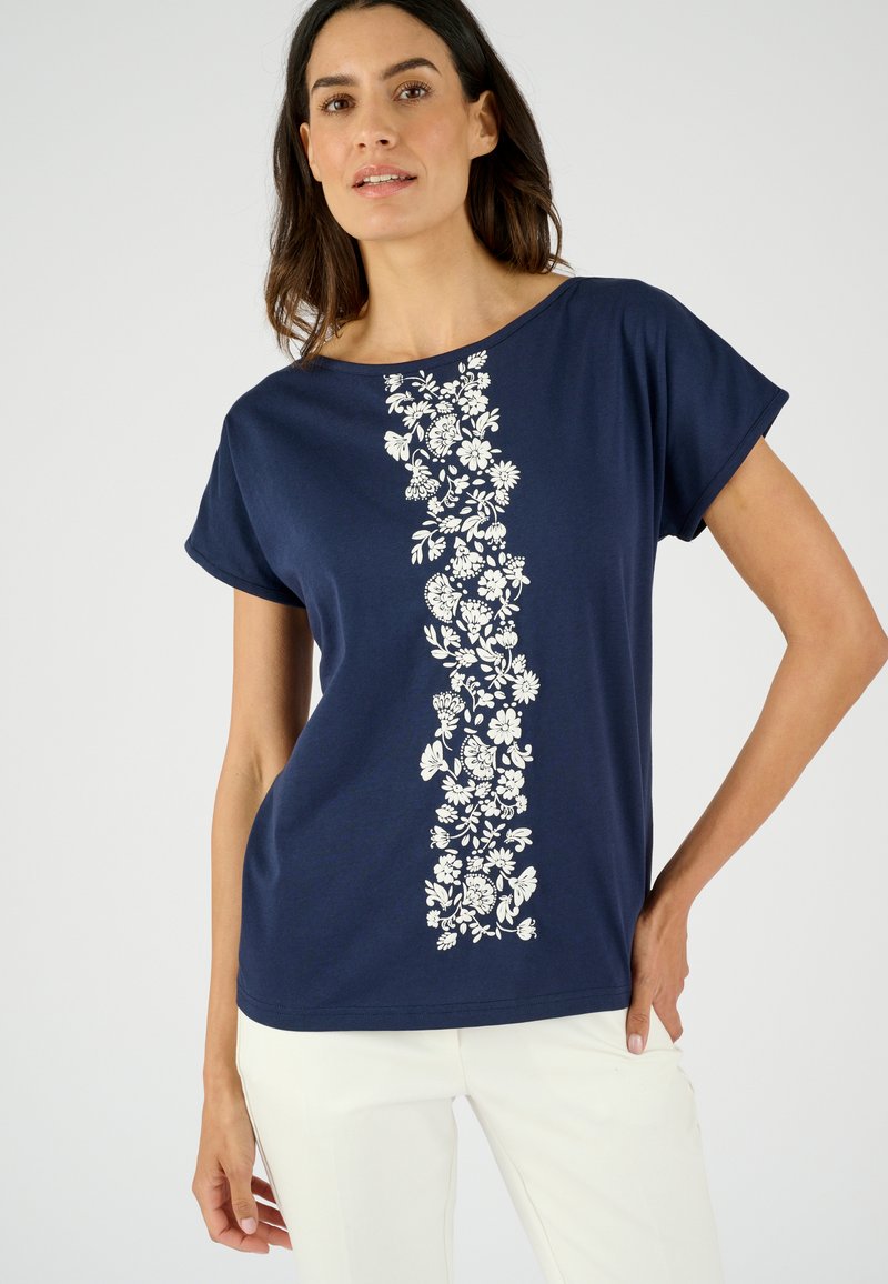 Camiseta de manga corta en color azul marino con un estampado floral blanco en el centro. Material de algodón suave y corte relajado.