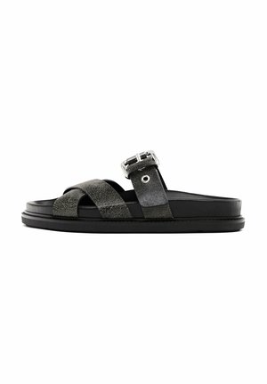 Sandale slide en cuir noir avec des brides croisées et une boucle métallique ajustable sur une semelle épaisse.