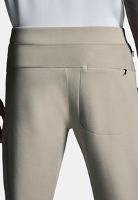 Lichtbeige sweatpants met een zachte stoftextuur, een brede tailleband en een achterzak met subtiele stikdetails.