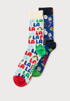 Deux chaussettes sur le thème de Noël, une blanche avec un texte coloré "LA" et du houx, l'autre bleue avec des bonshommes de neige, des cadeaux, des cannes en sucre d'orge et des bonshommes en pain d'épices.