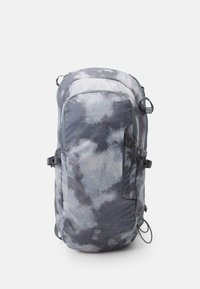 Mochila gris y negra con un patrón similar a nubes, que presenta correas ajustables, bolsillos laterales y un bucle superior para colgar. Tela duradera.